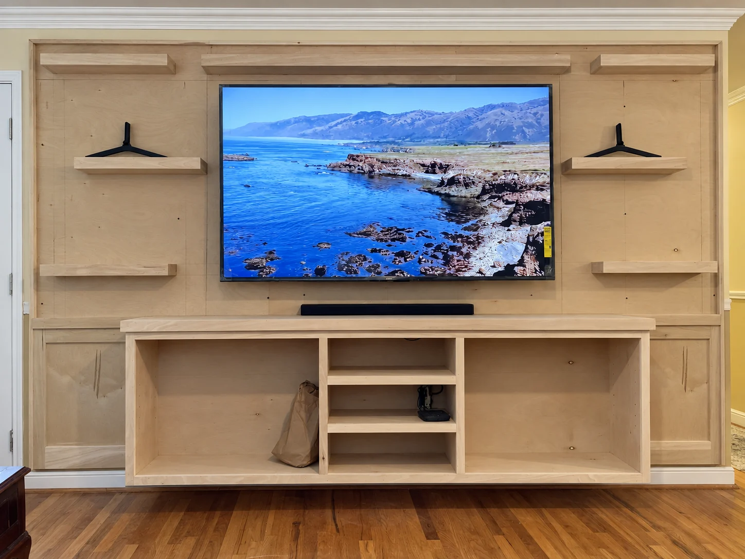 Media wall cabinet shell with open shelves and unfinished surrounding wall during installation