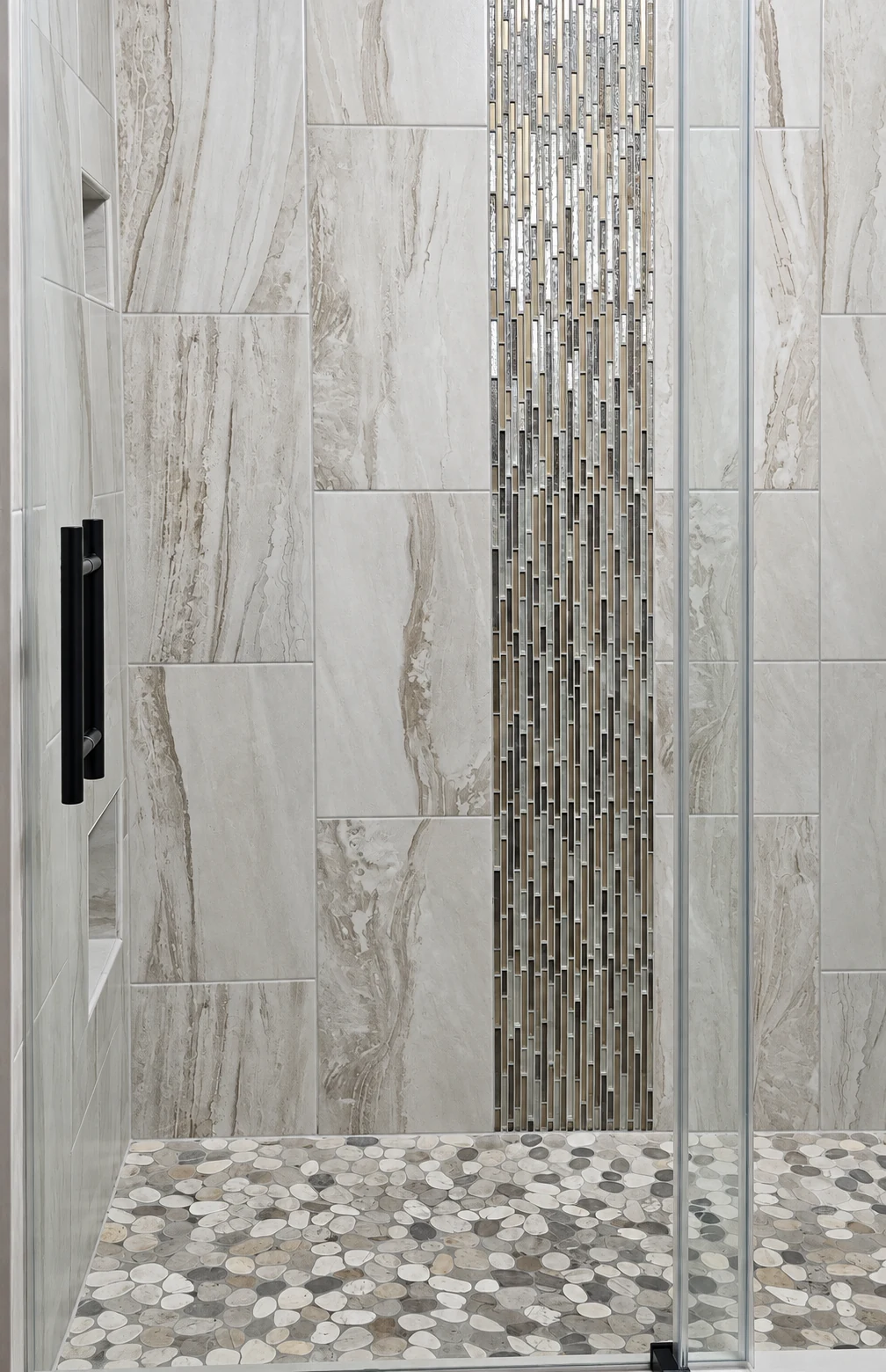 Close view of shower tile, mosaic, glass, and pebble floor